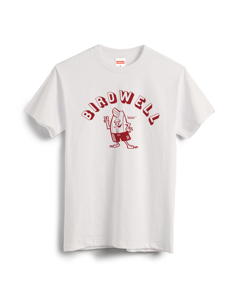 The Jim T-Shirt - Vintage White features “BIRDWELL” in red, arched over a red cartoon bird flashing two fingers and wearing shorts. The brand name is also displayed on the neck tag.