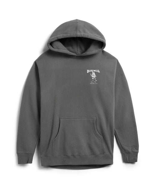 The 61 Hoodie - Faded Black is a relaxed fit, dark gray hoodie with a front pocket. The left chest has a small white screen-print reading BIRDWELL above a winged bomb graphic, plus additional small text underneath.
