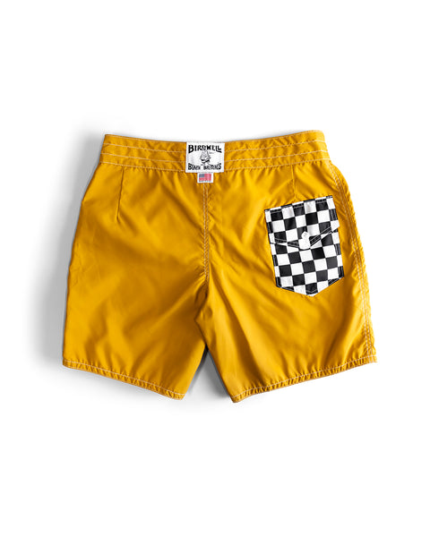 Checkmate Gold 300 Boardshorts feature yellow SurfNyl fabric, a black and white checkered back pocket, and a center Birdwell label on the waistband. These classic, water-repellent boardshorts are made in the USA and displayed flat on a white background.
