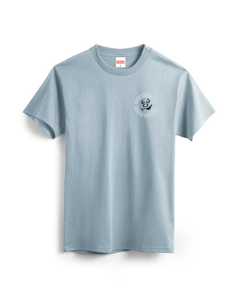 The Rounder T-Shirt - Arctic Blue is a light blue garment-dyed tee with short sleeves and a small circular 