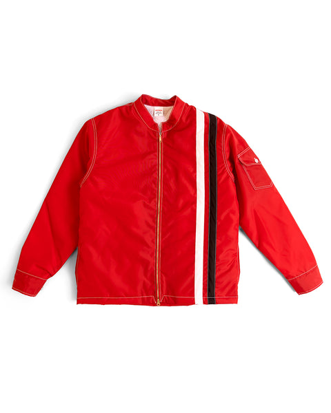 The Quilt Lined Racing Jacket - Red/White/Black is a bright red zip-up with a stand collar, vertical white and black stripe on one side, and a flap pocket on the left sleeve, shown against a white background.