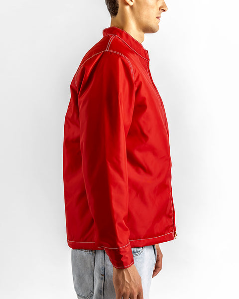 A person wearing a Quilt Lined Racing Jacket - Red/White/Black and light blue jeans is standing sideways, facing right, against a plain white background.