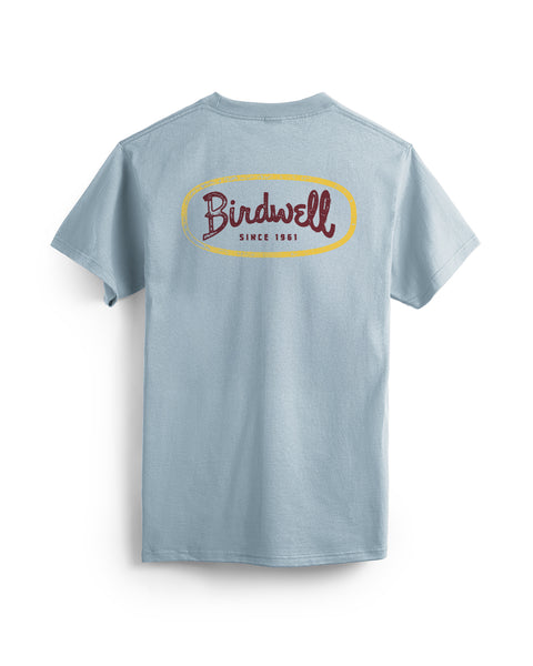 The Potato T-Shirt in Arctic Blue is a light blue, garment-dyed cotton tee shown from the back with a large vintage-style Birdwell Since 1961 logo in red and yellow across the upper back.