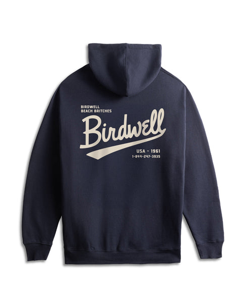 The Baller Hoodie - Navy is a heavyweight, relaxed-fit hoodie shown from the back, with a bold screen print: large white “Birdwell” script and smaller “Birdwell Beach Britches, USA • 1961,” plus a phone number.