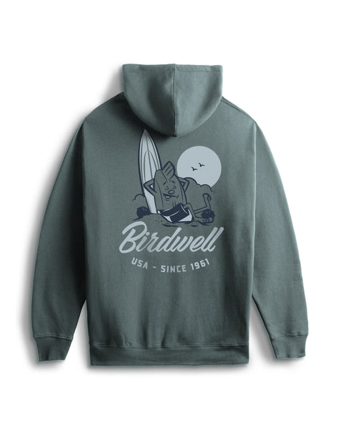 The Pau Hoodie in Atlantic Blue offers a relaxed fit and features a back screen-print of a cartoon cat with a surfboard by the ocean, full moon, flying birds, and the text 