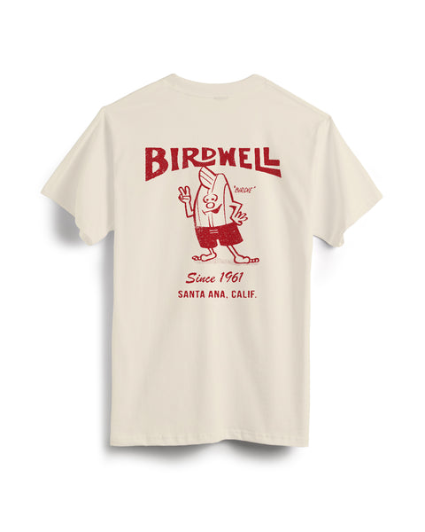 The 61 T-Shirt - Cream is a garment-dyed cotton tee featuring a red cartoon surfer and vintage BIRDWELL graphics on the back, including 
