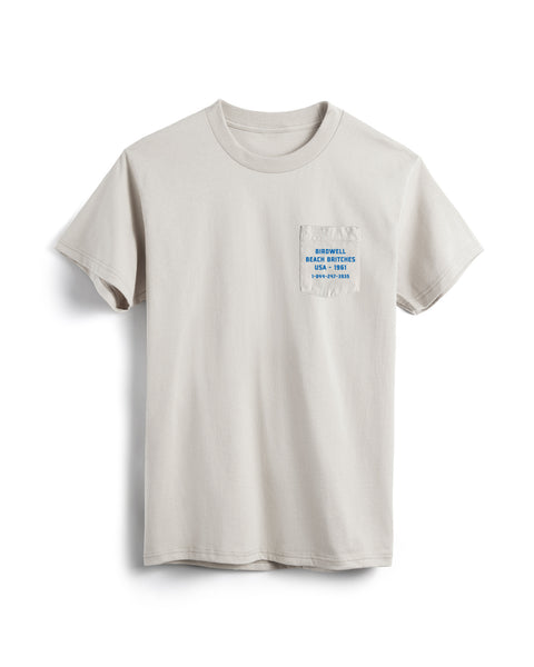 The Van Life Pocket T-Shirt - Cement is a heavyweight, garment-dyed t-shirt in light beige with a front pocket and small blue text: Begin Well. Break Rules. Be Grateful. EST. 1995.