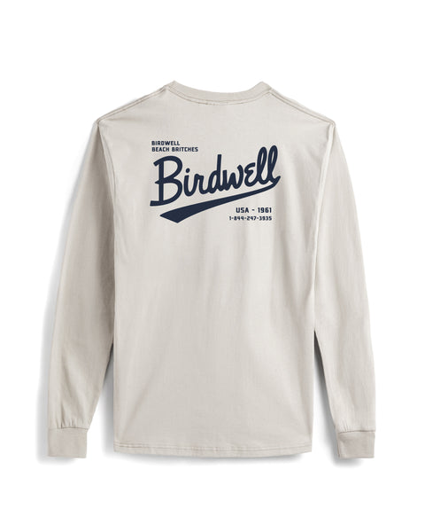 The Baller Long Sleeve Pocket T-Shirt in Cement is a heavyweight cotton tee featuring bold navy “Birdwell” and “Beach Britches USA - 1961” with contact info on the back. Shown laid flat, highlighting its pocket and back print details.