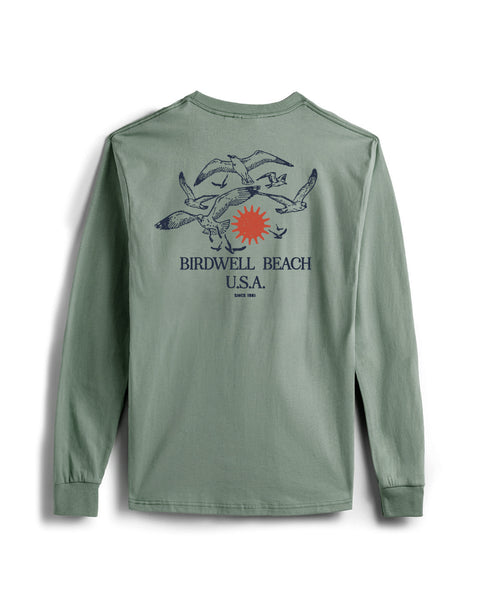 The Tourist Long Sleeve Pocket T-Shirt - Atlantic Green is a sage green cotton tee with a back graphic of two blue crabs, a red sun, and the text “BIRDWELL BEACH U.S.A. SINCE 1961.” Proudly made in the USA.