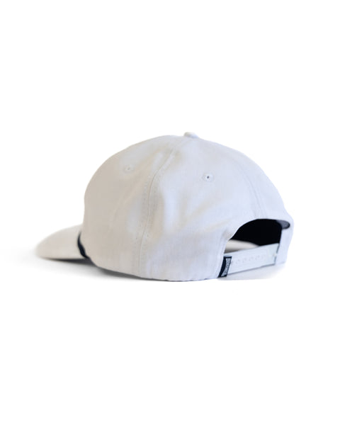 The Tourist Twill Snapback - White is a 5 panel hat shown from the back, with a black adjustable strap and a small tag, set against a plain white background.
