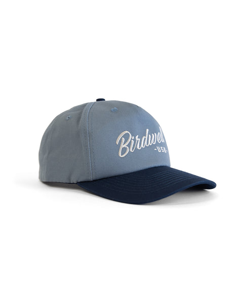 The Script Twill Snapback - Federal Blue/Bone is a two-tone, 5-panel cotton hat with a light blue crown and dark blue brim. 