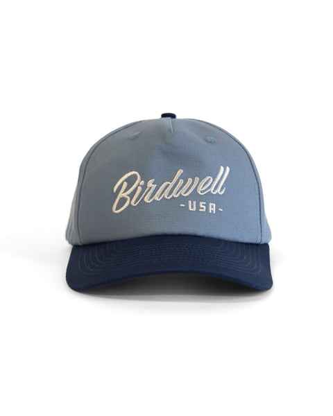 The Script Twill Snapback - Federal Blue/Bone is a light blue cotton snapback hat with a dark blue brim and features 