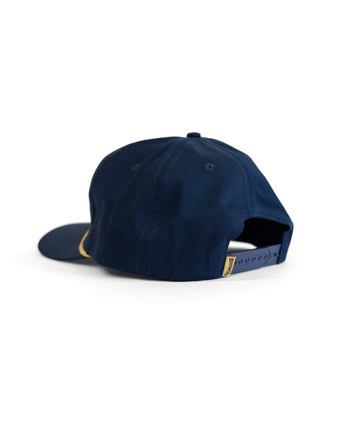 The Potato Patch Twill Snapback - Navy is a high-crown cotton snapback hat, shown from the back on a white background, featuring an adjustable snap closure and a small yellow tag on the strap.