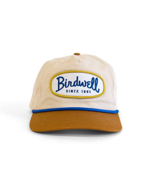 The Potato Patch Twill Snapback - Bone/Brown is a beige 5-panel hat with a brown brim, featuring a front stitched oval patch reading 