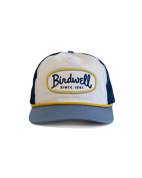 The Potato Patch Twill Snapback - Bone/Federal Blue is a white and blue 5-panel hat with a light blue brim, yellow trim, and an embroidered 