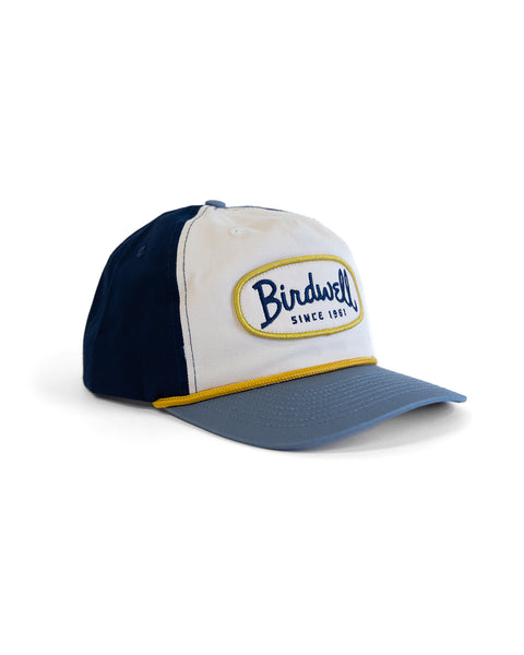 The Potato Patch Twill Snapback - Bone/Federal Blue is a blue and white 5-panel hat with a curved brim, yellow-bordered 
