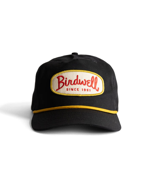 The Potato Patch Twill Snapback - Black is a 5-panel hat with yellow trim and a white front patch featuring 