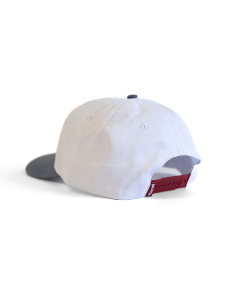 The Big Arc Twill Snapback - White/Federal Blue is a 5-panel cotton hat with a white crown, gray brim, six stitched eyelets, and an adjustable red snapback closure. Shown from the back against a plain white background.