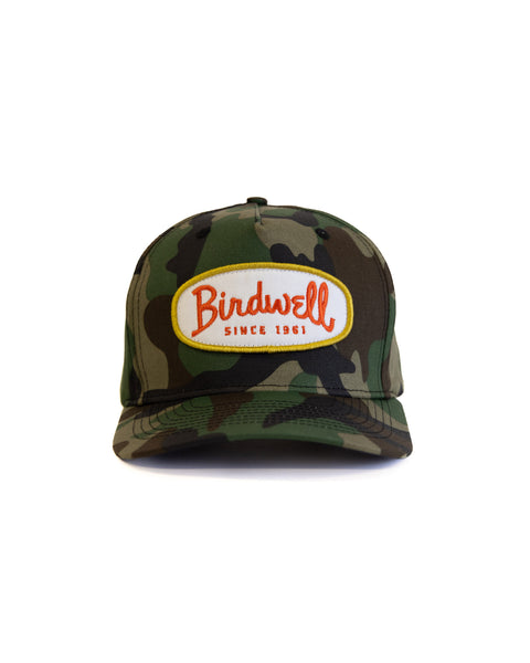 The Potato Patch Twill Snapback - Woodland Camo is a 5-panel cotton hat in camouflage, featuring a front white and orange patch with 