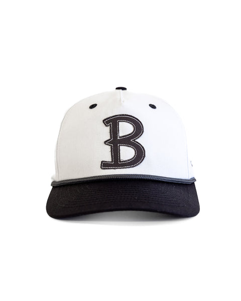 The Big B Twill Snapback - White/Black is a 5-panel hat featuring a black brim and a bold black embroidered letter B on the front, shown against a white background.
