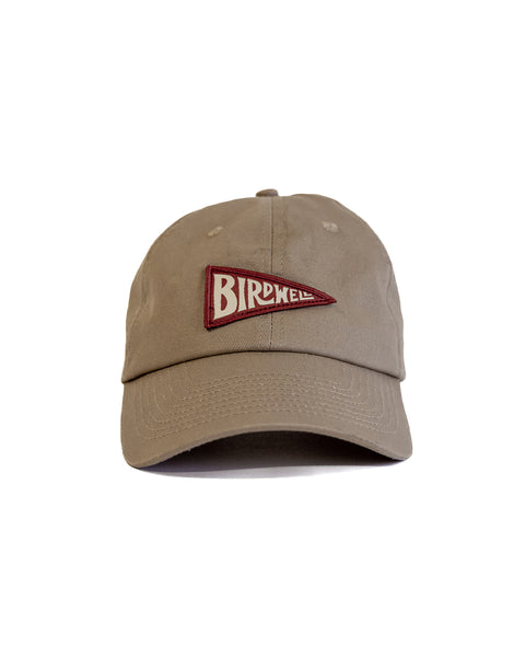 The Daddy Twill Hat - Sand is a beige cotton dad hat with an unstructured design, featuring a red and white pennant patch labeled 
