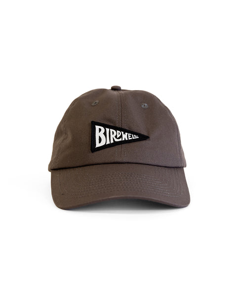 The Daddy Twill Hat - Washed Black is an unstructured dad hat featuring a black triangular patch with the word BIRDWELL in bold, white letters on the front, displayed against a plain white background.