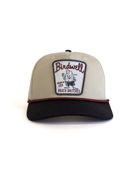 The Milkman Twill Snapback - Bone/Black is a 5-panel hat with a front patch that says 
