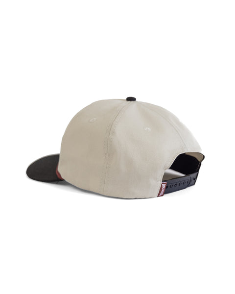 The Milkman Twill Snapback - Bone/Black is a beige (bone) 5 panel cotton hat with a black brim and adjustable black strap at the back, shown on a white background.