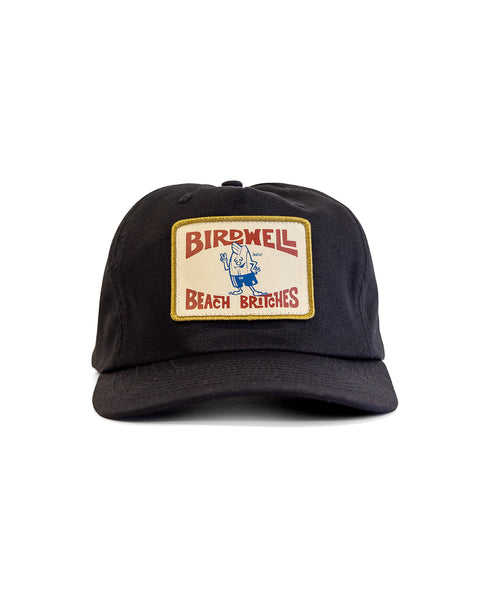 The OG Twill Snapback - Black is a high crown, 5-panel unstructured hat with a yellow-bordered rectangular patch reading BIRDWELL BEACH BRITCHES and featuring a cartoon blue bird character for classic style and comfort.