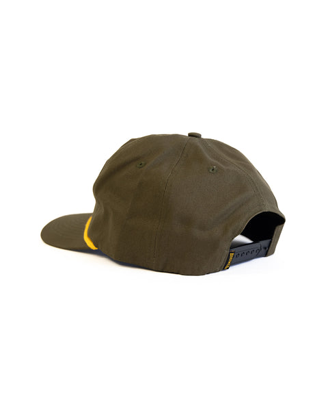 The Shield Twill Snapback - Olive is a dark green 5-panel cap shown from the back, featuring a black adjustable snapback strap and a partial yellow accent on the side, all set against a white background.