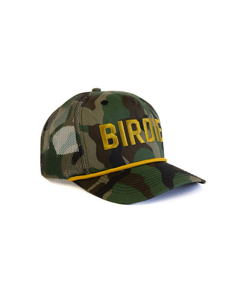 The Big Birdie Twill Trucker - Woodland Camo is a green and brown cotton snapback with black mesh sides and back. This unstructured 5-panel cap has BIRDIE embroidered in large yellow letters on the high crown front.