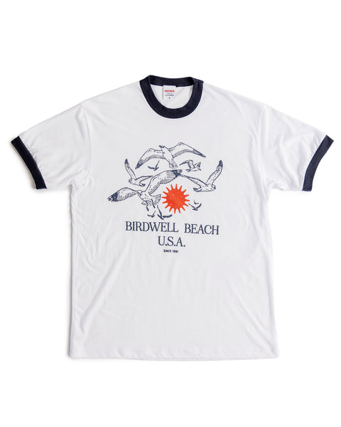 The Tourist Ringer T-Shirt - Navy/White features navy collar and sleeve trim, flying birds, an orange sun, and 