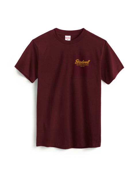 The Daydreamin Birdie T-Shirt in Burgundy is a heavyweight, garment-dyed tee featuring a small yellow Birdwell logo and text on the left chest, shown on a white background.
