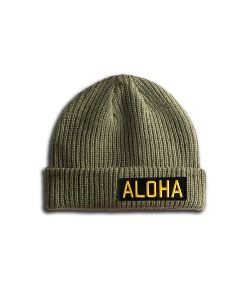 The Aloha Watchcap - Army is a ribbed, olive-green fisherman beanie with a folded brim and a bold yellow Aloha patch on black, shown against a clean white background.