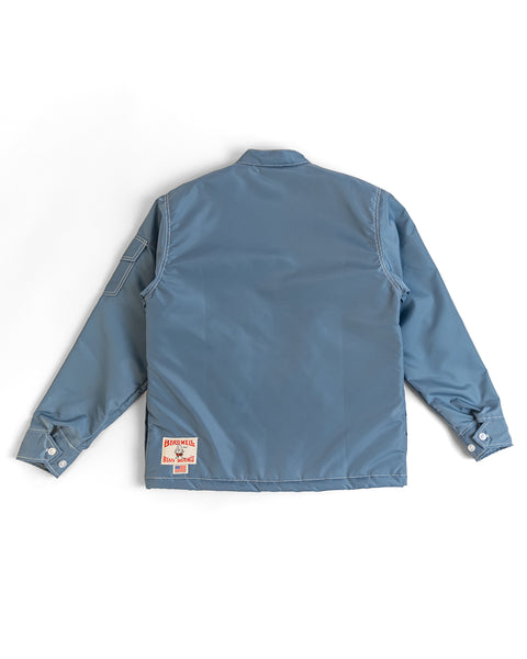 Quilt Lined Racing Jacket in Federal Blue/Bone/Navy laid flat, back view. Features long sleeves, a collar, buttoned cuffs, and a small rectangular patch near the left bottom hem.