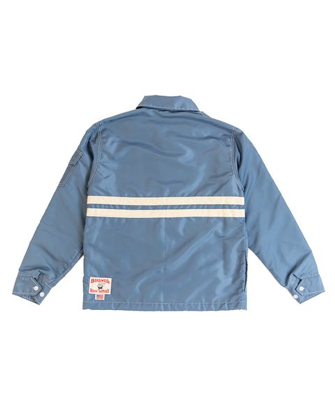 Federal Blue/Bone Comp Jacket 25 shown from the back, featuring two horizontal white reflective stripes, buttoned cuffs, a rectangular patch near the bottom right hem, and SurfNyl fabric for lasting American-made quality.