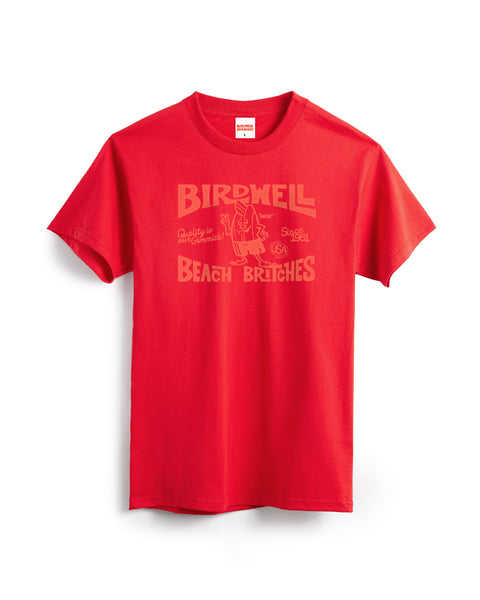 The Taggert T-Shirt - Fuji Red is a heavyweight, garment-dyed cotton tee featuring a vintage-style faded “Birdwell Beach Britches” print with small graphics, including a surfboard character, for softness and lasting color.