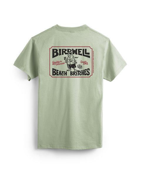 Desert green, garment-dyed cotton Hangtag T-Shirt with short sleeves and a large vintage-style Birdwell Beach Britches graphic on the back featuring a cartoon character in swimwear and stylized design elements.