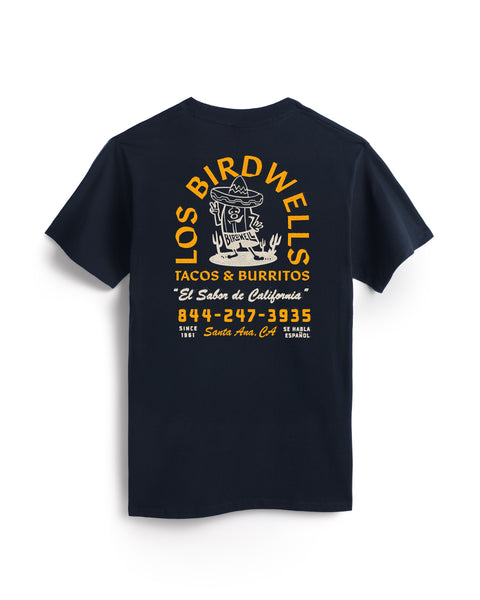 The Los Birdwells T-Shirt - Navy is a heavyweight cotton, garment-dyed tee with a yellow and white Los Birdwells Tacos & Burritos cartoon bird graphic, phone number, and Santa Ana, California callout on the back.