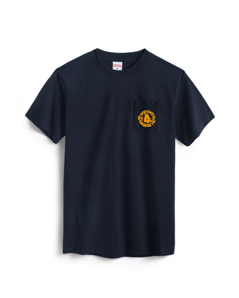 The Shaka Pocket T-Shirt - Navy is a short-sleeve cotton tee featuring a left chest pocket with a small yellow circular graphic and text.