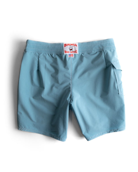 The 808 SurfStretch Side Pocket Boardshorts in light blue feature a red and white Birdwell label on the waistband, a right-side pocket, and are made in the USA. Shown flat on a white background.