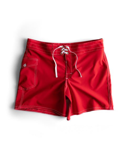 The 806 SurfStretch Side Pocket Boardshorts in bright red feature white stitching, a lace-up front closure, and a button-flap side pocket, shown against a white background.