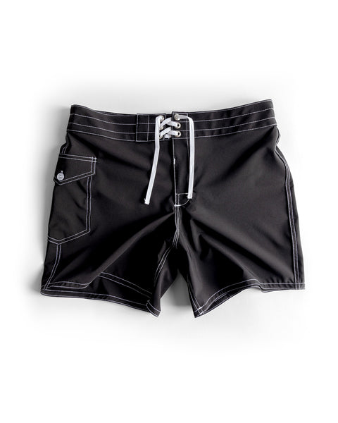 806 SurfStretch Side Pocket Boardshorts in black, featuring white stitching, a lace-up front closure, and a button-flap side pocket, shown laid flat on a white background.