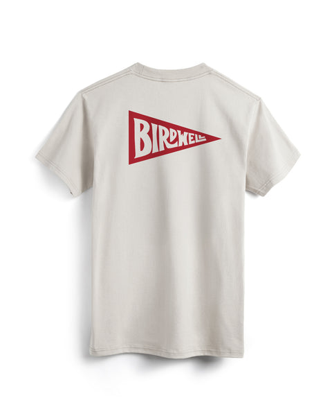 The Pennant Pocket T-Shirt - Cement is a heavyweight, light beige tee with a bold red pennant graphic featuring 