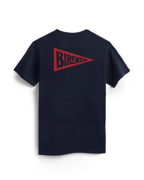 A navy heavyweight t-shirt with a red pennant-shaped graphic on the back featuring bold BIRDWELL lettering. The made-in-USA Pennant Pocket T-Shirt is shown laid flat on a white background.