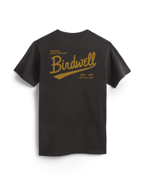 The Baller Pocket T-Shirt in Vintage Black is garment-dyed cotton, made in the USA, with a large gold Birdwell script on the back and smaller text: Birdwell Beach Britches, USA - 1961, 1-844-327-9533.