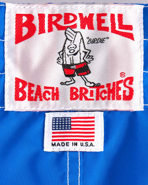 Close-up of a label on the 300 Boardshorts - Royal Blue shows a cartoon bird in red shorts with 