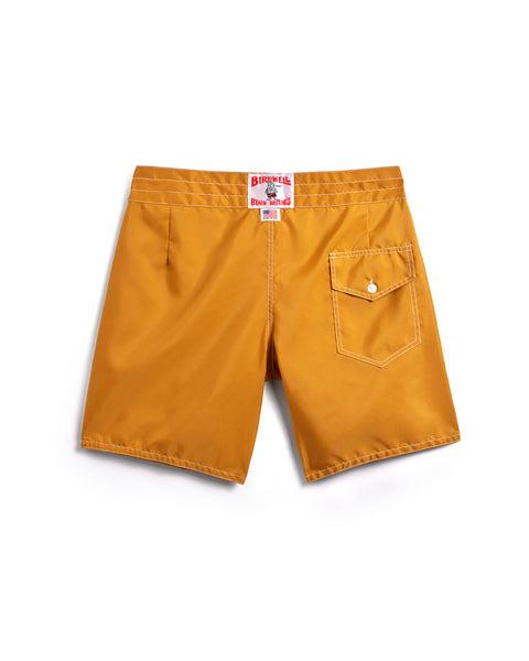 The 300 Boardshorts - Gold are shown from the back, featuring a mustard yellow color, a single right-side flap pocket with a button, and a red and white tag on the waistband.