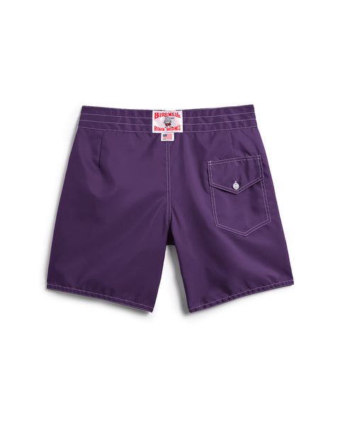 The 300 Boardshorts - Purple are shown from the back, featuring a single flap pocket with button on the right side and a red and white label above the waistband, proudly made in USA.