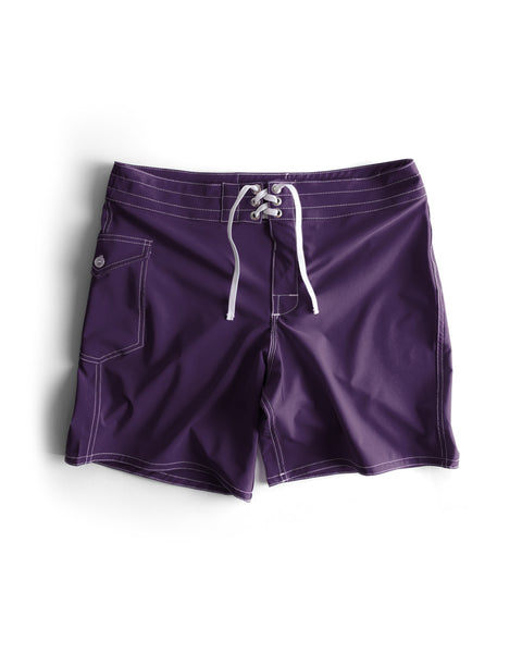 808 SurfStretch Side Pocket Boardshorts in purple feature a white drawstring, side pocket with button closure, and visible white stitching in a classic boardshort style. Made in USA. Shown on a white background.